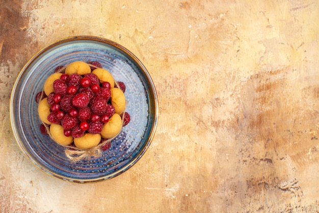 Freshly baked gift cake with fruits on the right side of mixed color table