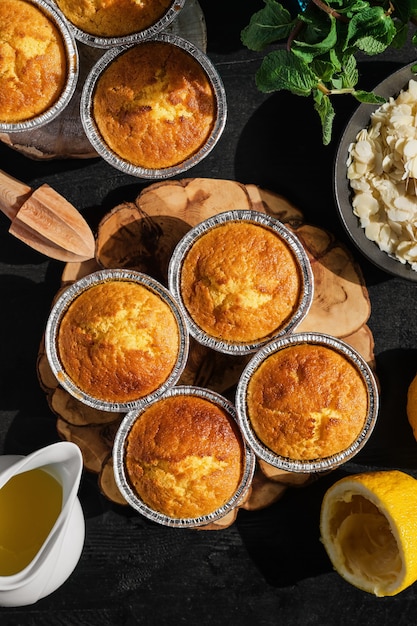 Freshly baked lemon muffins on black wooden table