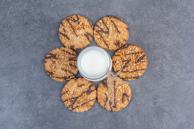 Biscotti di semi di sesamo appena sfornati e latte sul tavolo di marmo.