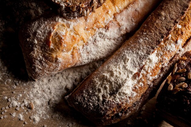 木製のテーブルに小麦粉と小麦粉と焼きたての伝統的なパン小麦粉と新鮮なバゲット Premium写真