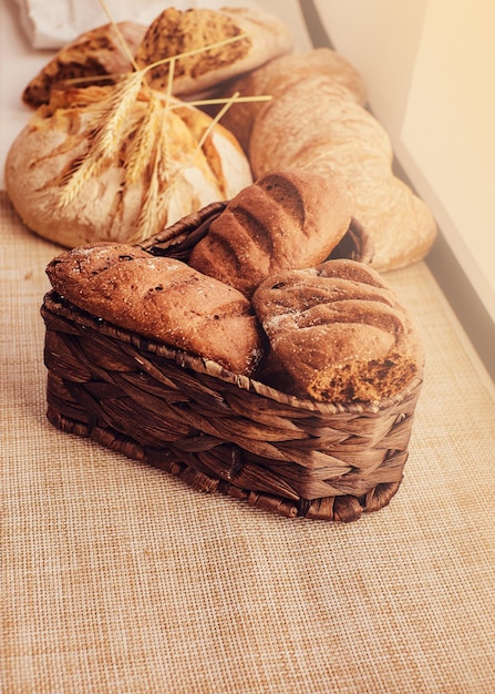 Freshly bakery products and spikelets on cloth at home. Close-up photo of freshly baked bread products.