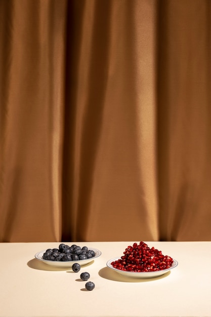 Свеже синие ягоды и сочные семена граната на столе перед коричневом фоне