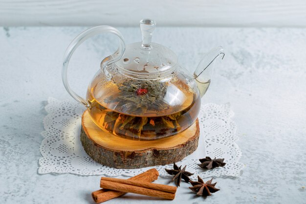 Freshly brewed tea. Teapot on wooden board over grey surface.