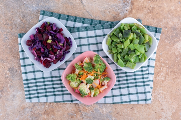 Freshly chopped vegetables mixed and bundled in bowls on marble surface`