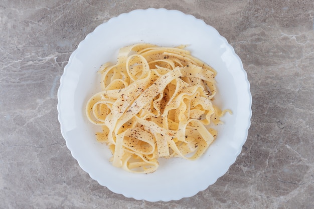 Freshly cooked spicy tagliatelle , on the marble surface.