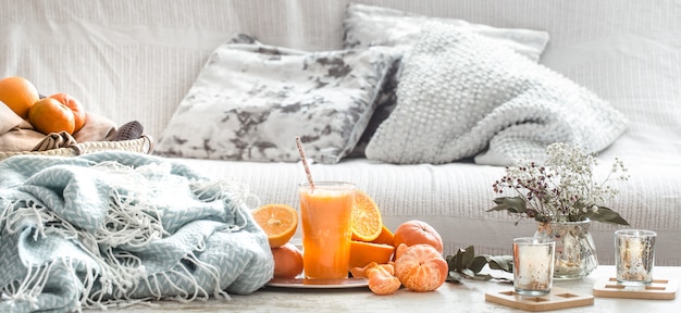 Freshly-grown organic fresh orange juice in the interior of the house, with a turquoise blanket and a basket of fruit