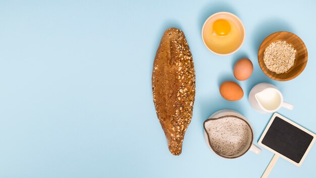 Freshly homemade bread; egg; oat barn; milk; flour and placard on blue backdrop