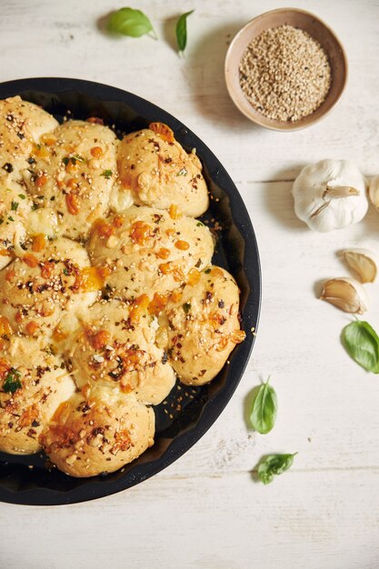 Freshly-made delicious cheese bubble pizza bread with ingredients and cheese on a white table