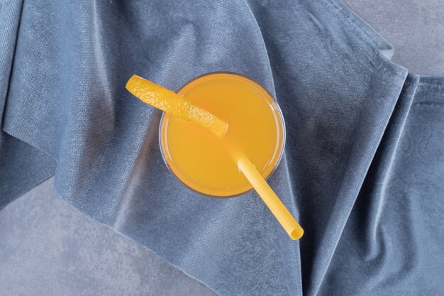 Свежеприготовленный апельсиновый сок на сером фоне.