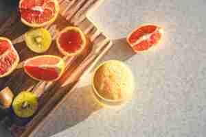 Foto gratuita succo appena spremuto in un bicchiere e frutta fresca sul tavolo della cucina