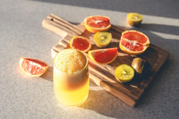 Freshly squeezed juice in a glass and fresh fruit on the kitchen table