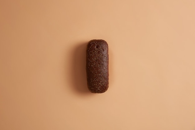 Freshy baked rye bread of rectangular shape garnished with cumin, prepared from organic flour, has aromatic smell, appetizing look. Beige background. Nourishing product. Food concept. Flat lay