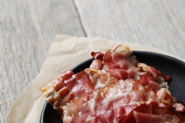 Fried bacon on black plate