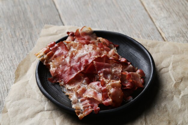 Fried bacon on black plate