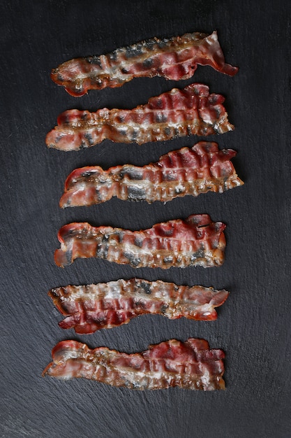 Free photo fried bacon on black stone table