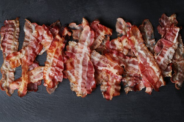 Fried bacon on black table, top view