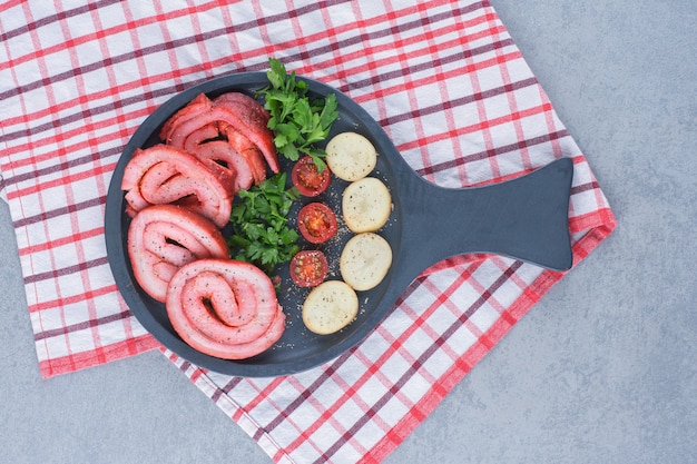 Fried bacon with potato on black frying pan. 