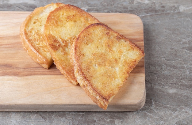 Fried bread with egg on wooden board.