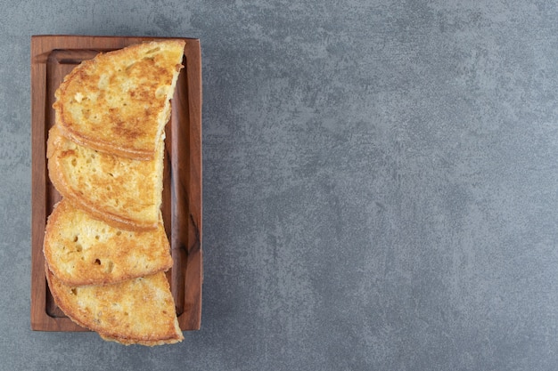 Fried bread with egg on wooden board.