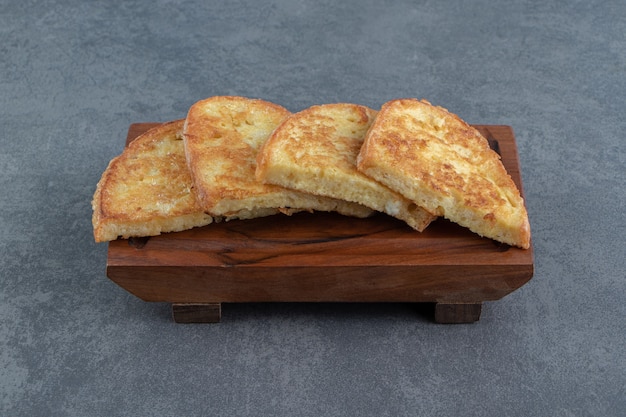 Fried bread with egg on wooden board.