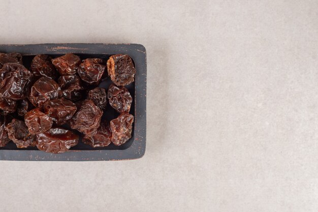 Fried brown sour cherries on a wooden platter.