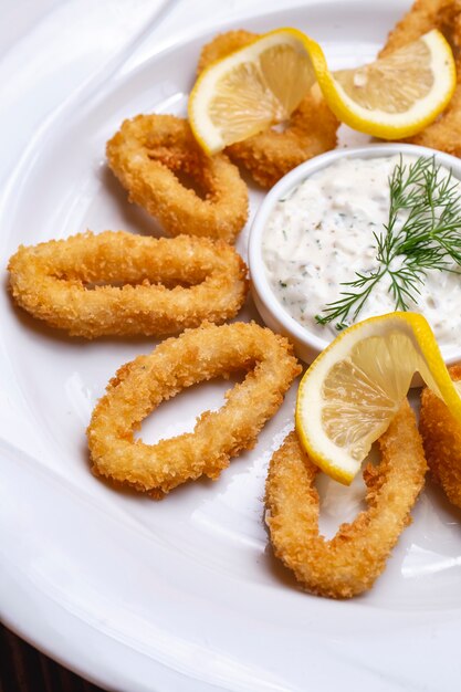 Fried calamary in breadcrumbs lemon tartar sauce dill side view