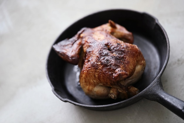 Жареный цыпленок на черной сковороде