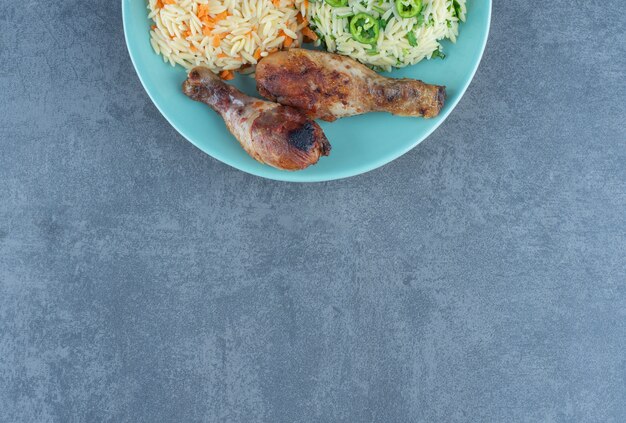 파란색 접시에 튀긴 닭 다리와 쌀.
