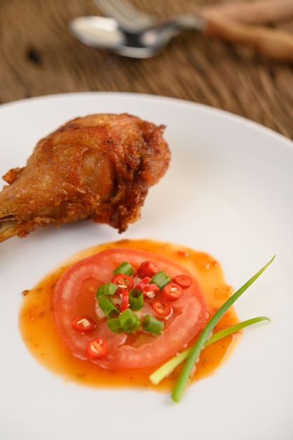 Жареные куриные ножки на белой тарелке с соусом.