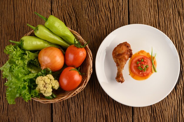 Жареные куриные ножки на белой тарелке с соусом.