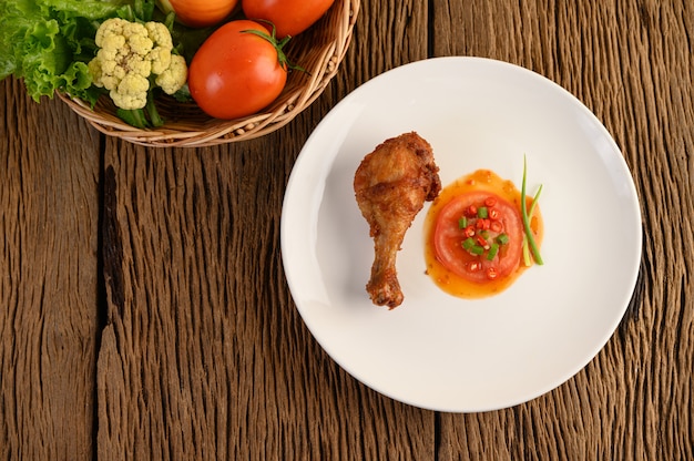 Fried chicken legs on a white plate with sauce.