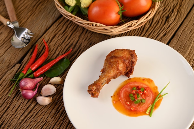 Fried chicken legs on a white plate with sauce.