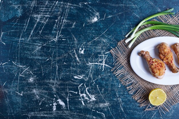 Foto gratuita cosce di pollo fritte in un piatto bianco.