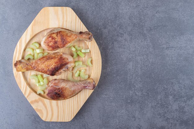 Fried chicken legs on wooden plate.