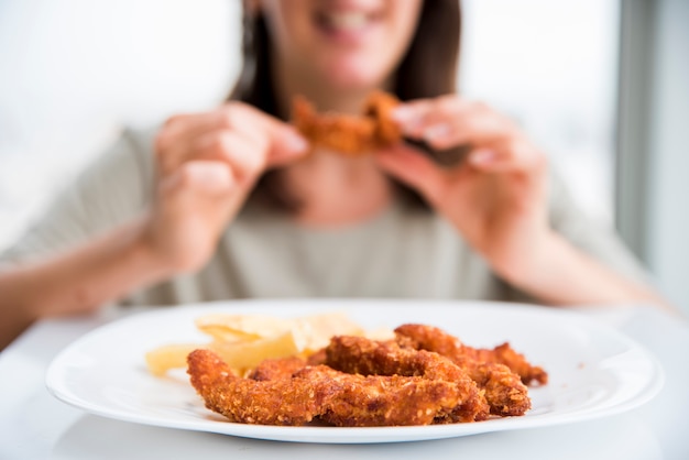 食べる女性の近くのフライドチキン