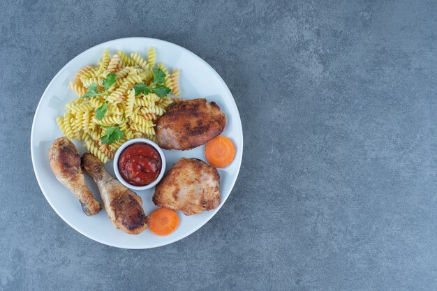 Fried chicken parts and fusilli on white plate. 