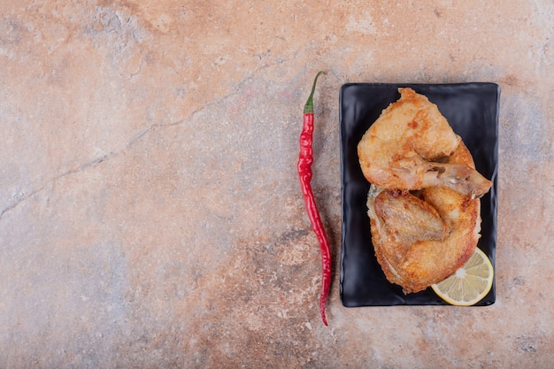 Free photo fried chicken pieces with hot chili peppers.
