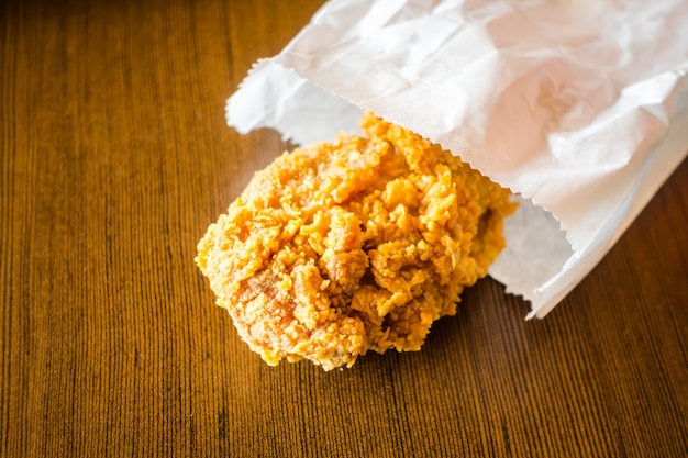 Fried Chicken Wings in paper bag on wood table .