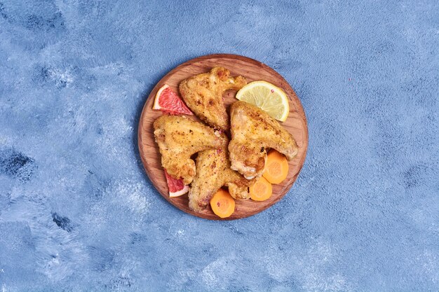 Fried chicken wings on a wooden board on blue