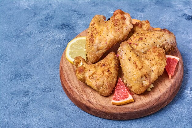 Fried chicken wings on a wooden board on blue