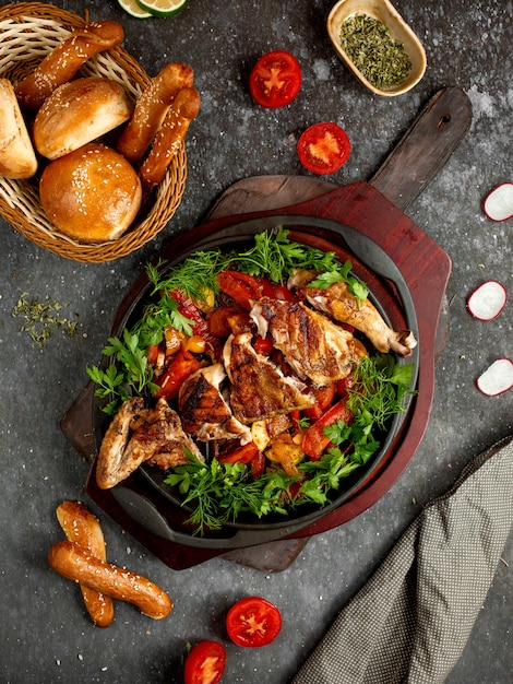 Fried chicken with vegetables and herbs in an aluminum skillet