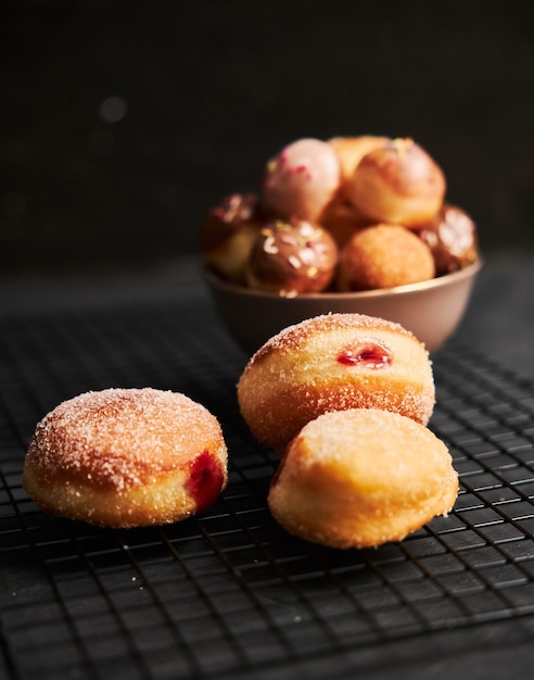 Fried donuts with sugar and cream on a black table