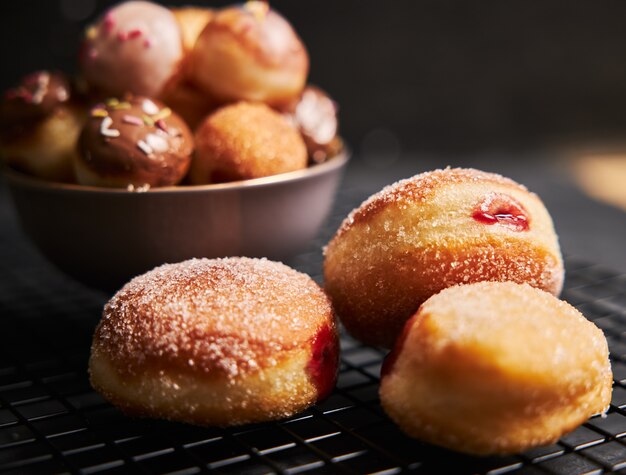 Fried donuts with sugar and cream on a black table