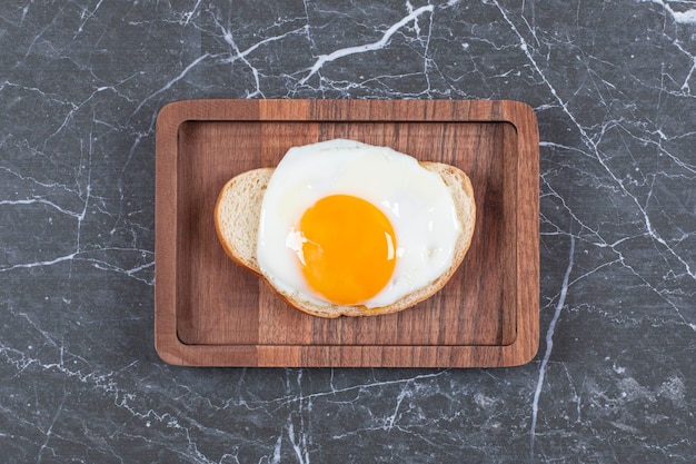 Fried egg on bread sliced on the board , on the marble surface