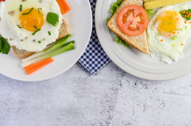 A fried egg laying on a toast, topped with pepper seeds with carrots, baby corn and spring onions.