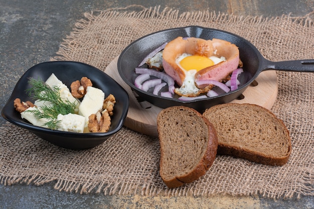 Fried egg on pan and cheese bowl with walnut kernels.