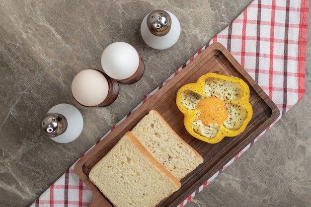 Foto gratuita uovo fritto in fette di pane e pepe sul piatto di legno. foto di alta qualità