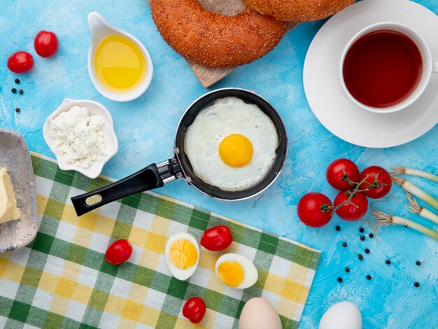 fried egg, tea and tomato on blue table