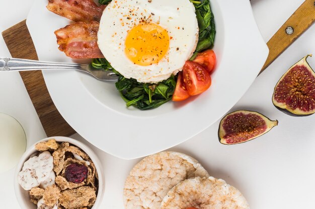 Fried egg with fig; rice puff cracker and cornflakes on white background