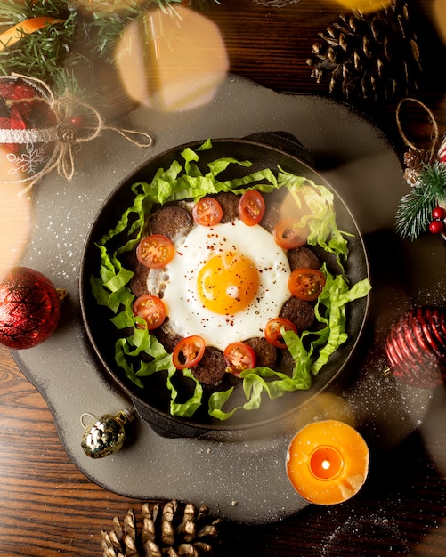 Free photo fried egg with fried sausages, tomatoes and lettuce